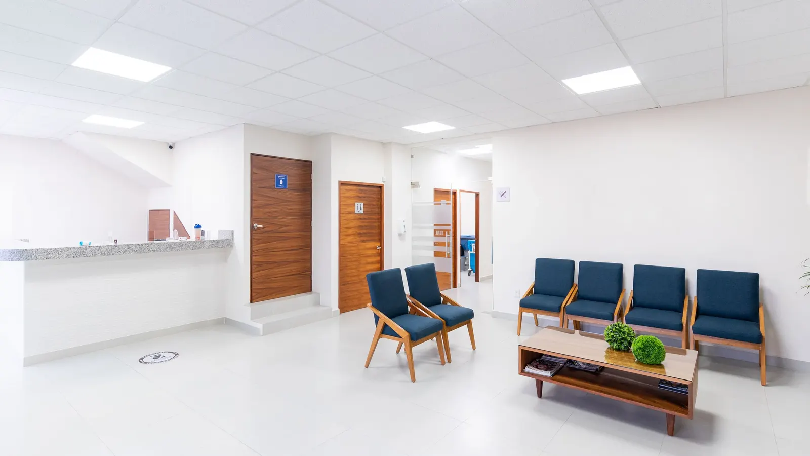Modern ve aydınlık bir klinik bekleme salonu, boş koltuklar ve resepsiyon bankosu
